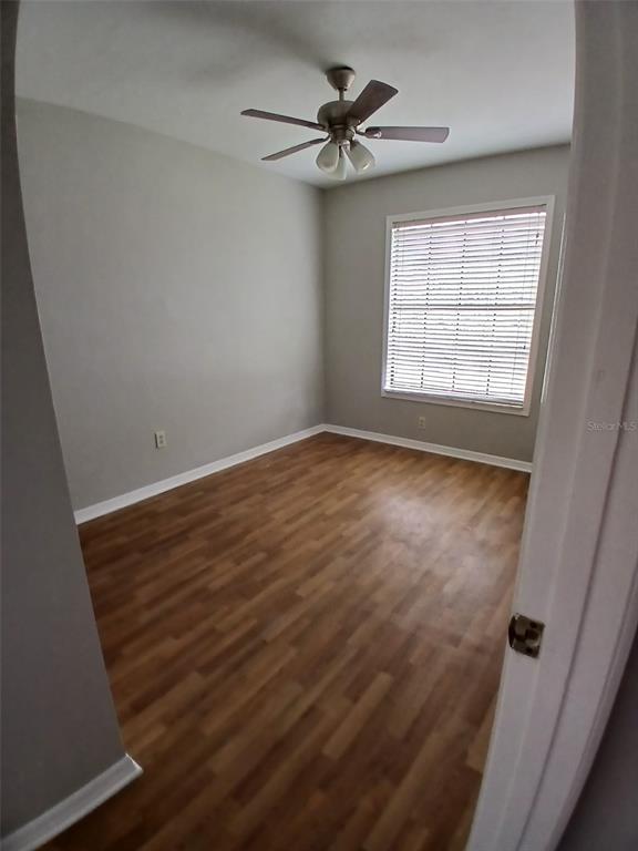 An empty bedroom features light gray walls, wood-look flooring, and a ceiling fan — 7454 WYNNEWOOD SQUARE UNIT 188, WINTER PARK, FL