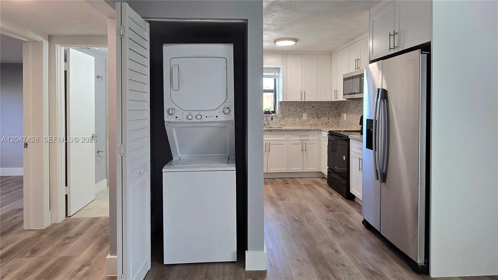 A stacked washer and dryer unit sits in a closet next to a modern kitchen — 50 W 28th St # 52, Hialeah FL 33010, HIALEAH, FL