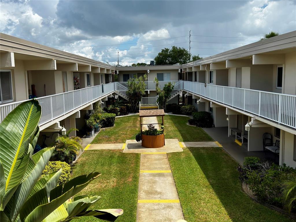 A concrete walkway leads to a set of stairs between two levels of apartment balconies — 6700 1ST AVENUE S UNIT 103, ST PETERSBURG, FL