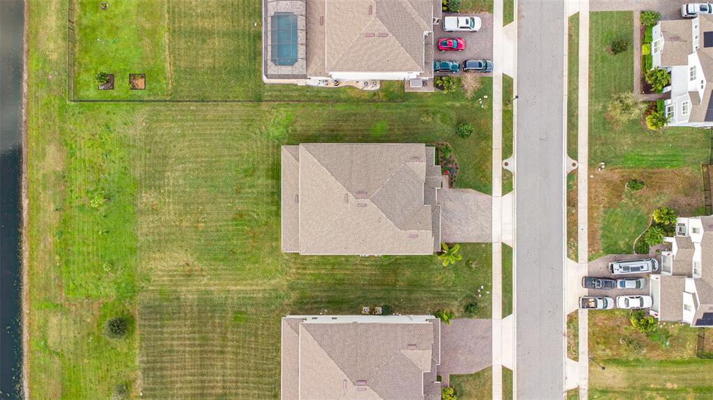 An aerial view shows three suburban houses with large backyards bordering a body of water — 2206 WEATHERLY WAY, ORLANDO, FL