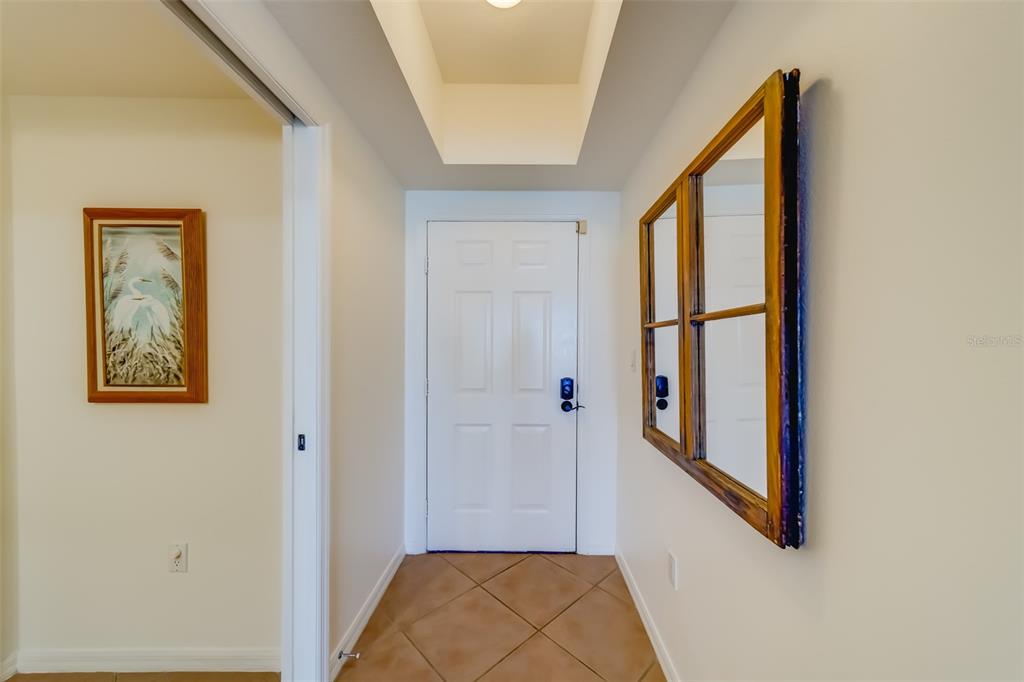 An entryway features a white door, tile flooring, a framed mirror, and a wall art piece — 16550 GULF BOULEVARD UNIT 643, NORTH REDINGTON BEACH, FL