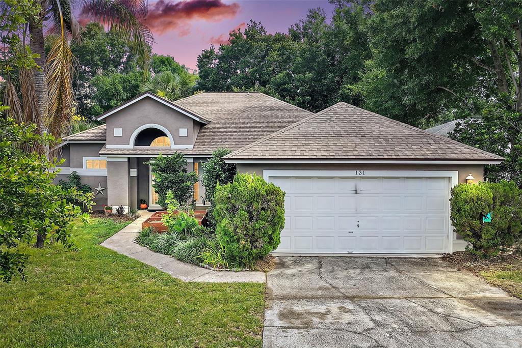 A single-story house with a gray exterior, a two-car garage, and a concrete driveway — 131 MADRONA DRIVE, EUSTIS, FL