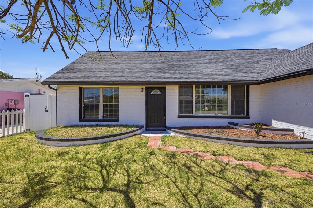 A white brick house with a dark roof and a front walkway leading to the door — 13615 GARRIS DRIVE, HUDSON, FL