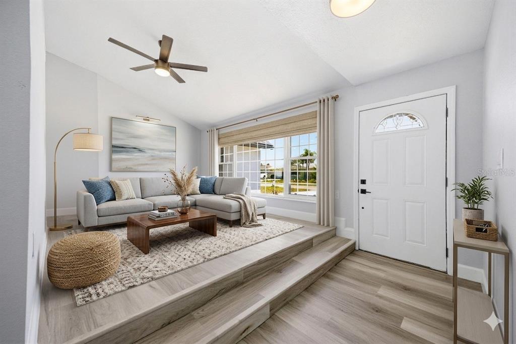 A living room features a sunken seating area with light wood flooring and a sectional sofa — 13615 GARRIS DRIVE, HUDSON, FL