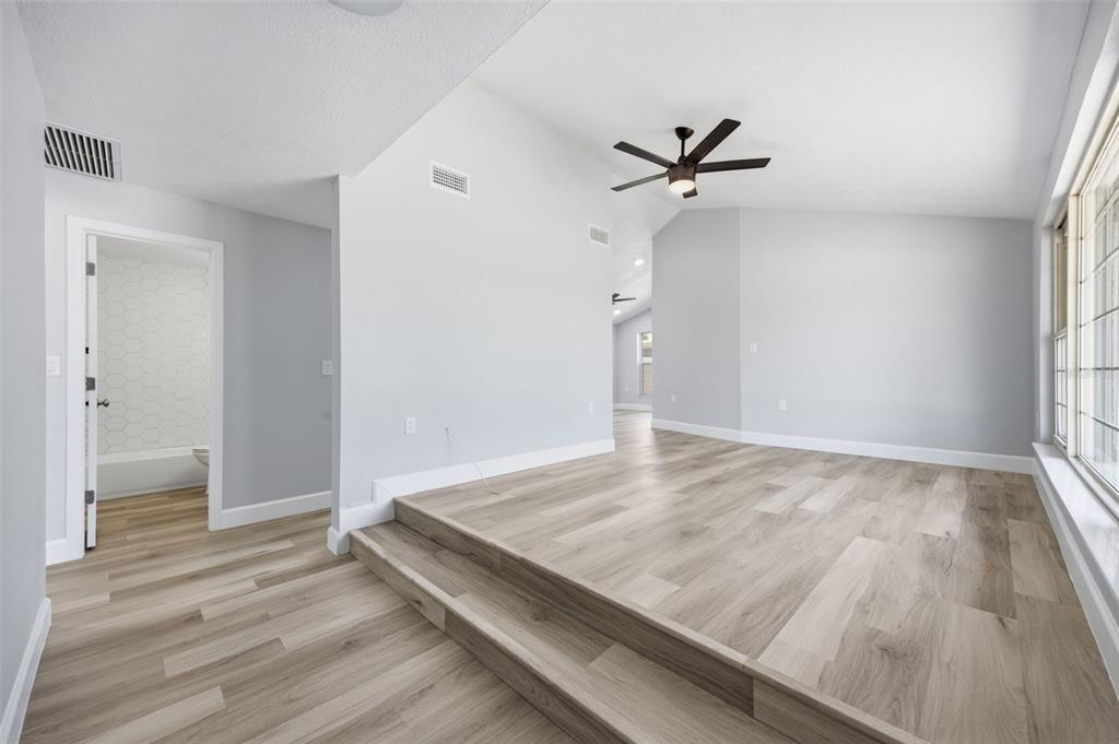 A living room features a raised floor section, light wood-look flooring, and a ceiling fan — 13615 GARRIS DRIVE, HUDSON, FL