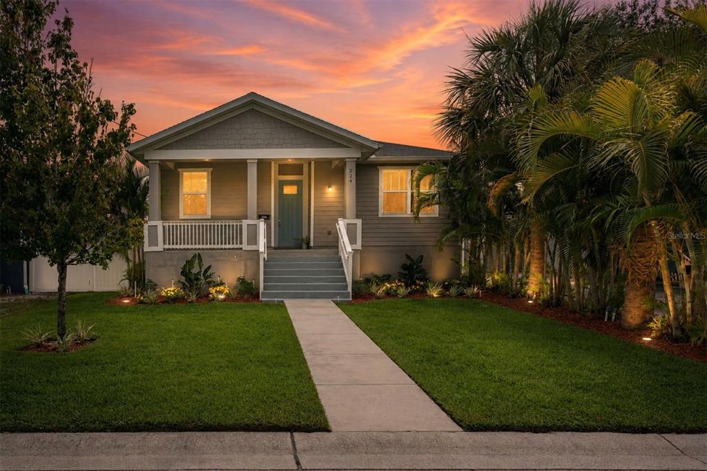 A single-story house with gray siding, a front porch, and a walkway at sunset — 224 NE JEFFERSON CIRCLE N, ST PETERSBURG, FL