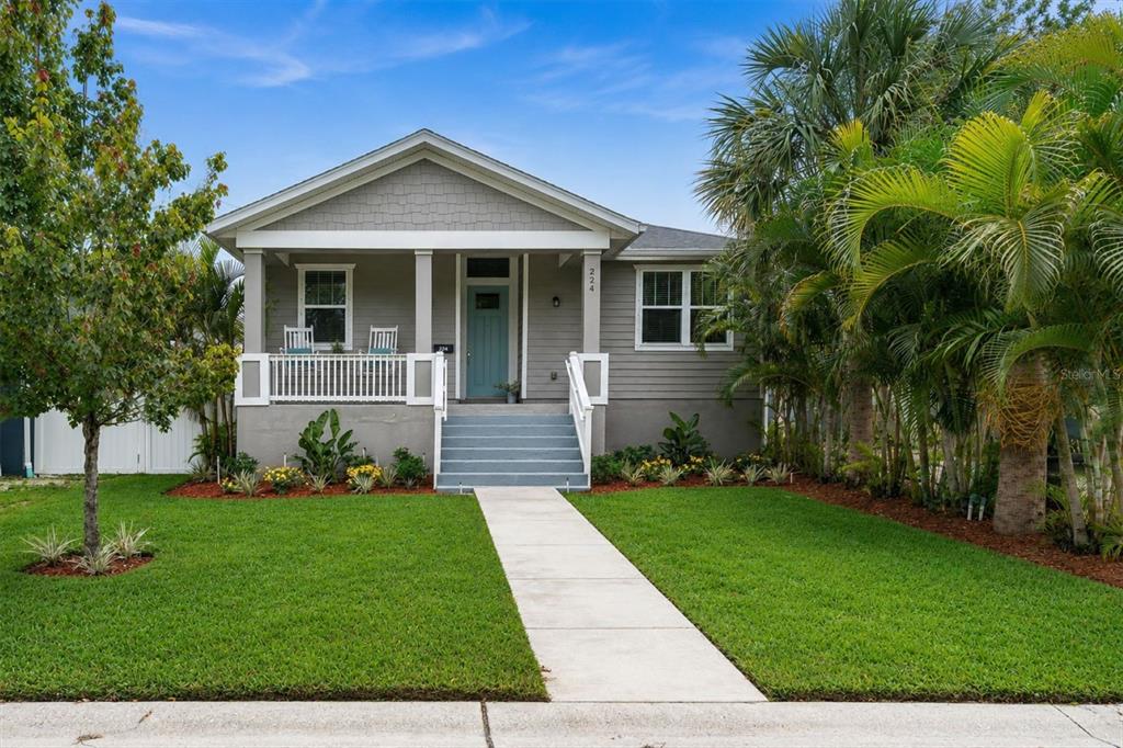 A gray, single-story house with a front porch, white railings, and a concrete walkway — 224 NE JEFFERSON CIRCLE N, ST PETERSBURG, FL