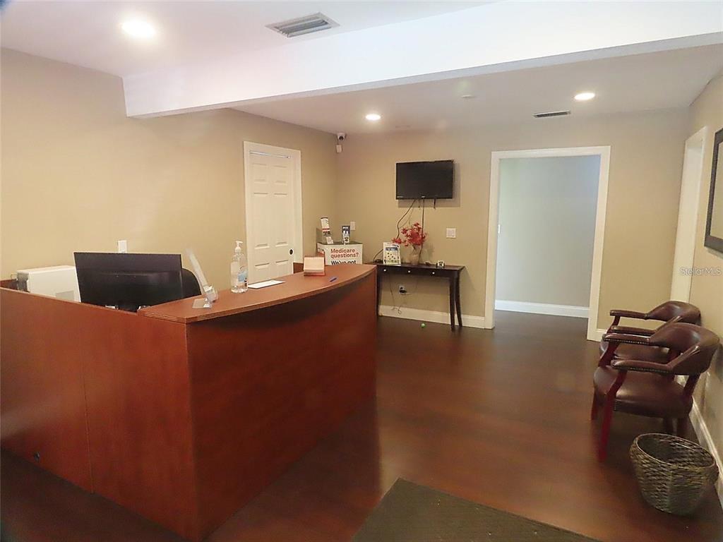 A reception area features a wooden desk, dark flooring, and two leather chairs — 657 MAITLAND AVENUE, ALTAMONTE SPRINGS, FL