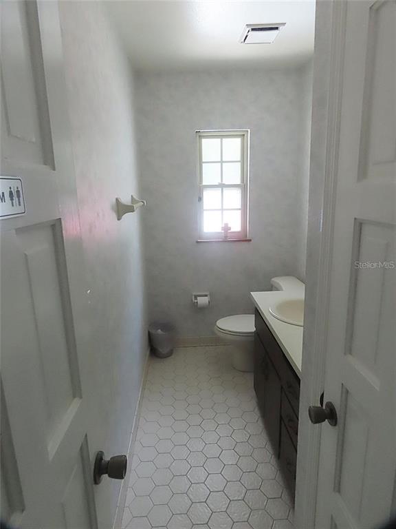 A small bathroom features a white vanity, a toilet, and white hexagonal floor tiles — 657 MAITLAND AVENUE, ALTAMONTE SPRINGS, FL