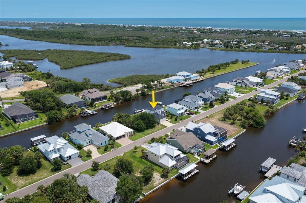 An aerial view shows a waterfront residential neighborhood with a yellow arrow marking a house — 121 SEASIDE POINT, FLAGLER BEACH, FL