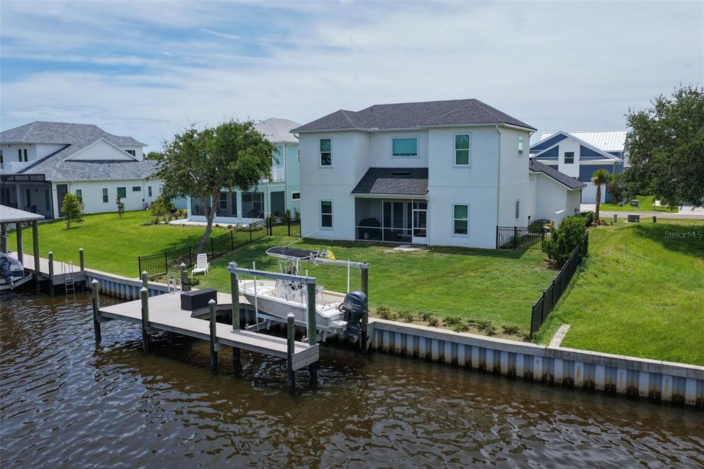 An aerial view shows a two-story house with a boat lift on a canal — 121 SEASIDE POINT, FLAGLER BEACH, FL