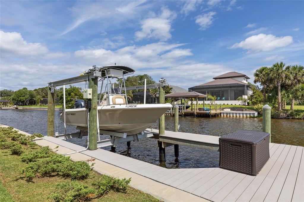 A boat on a lift sits at a dock along a canal near a house — 121 SEASIDE POINT, FLAGLER BEACH, FL