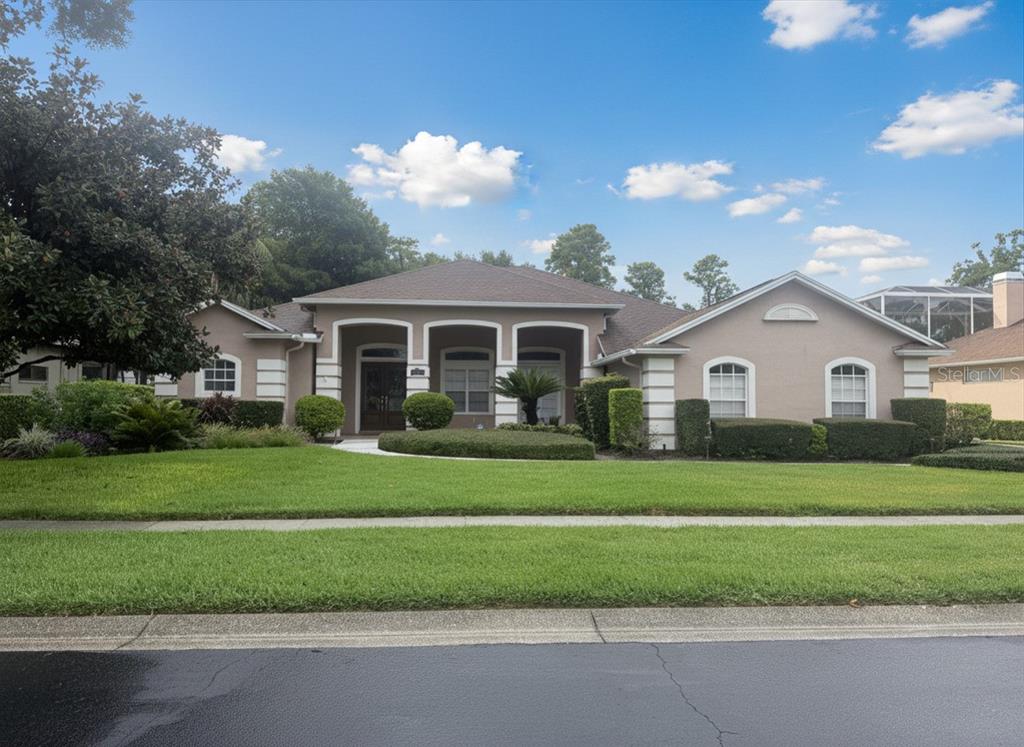 A single-story suburban house with a tan stucco exterior, arched windows, and a manicured lawn — 3704 SWANS LANDING DRIVE, LAND O LAKES, FL