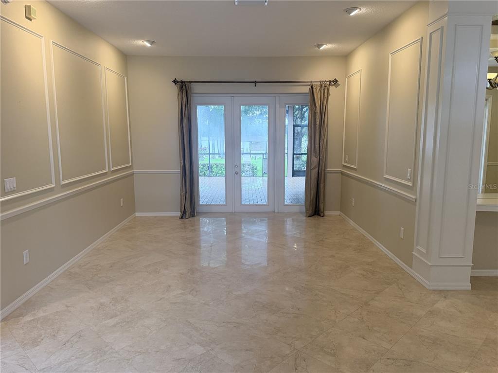 A dining room features beige walls with wainscoting, tile flooring, and glass doors to a patio — 3704 SWANS LANDING DRIVE, LAND O LAKES, FL