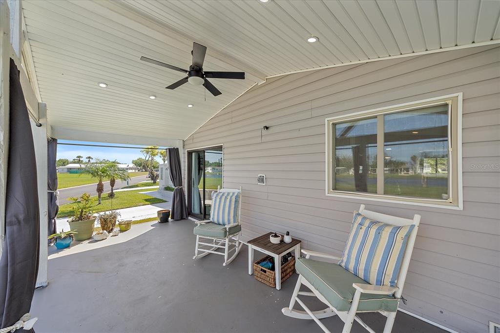 A spacious covered patio features a concrete floor, multiple seating areas, and light gray siding — 137 LAKEVIEW DRIVE UNIT 137, PALMETTO, FL