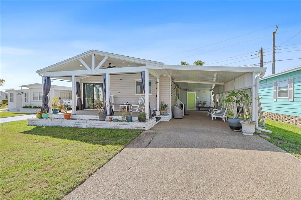 A covered patio features a ceiling fan, recessed lighting, two rocking chairs, and gray siding — 137 LAKEVIEW DRIVE UNIT 137, PALMETTO, FL