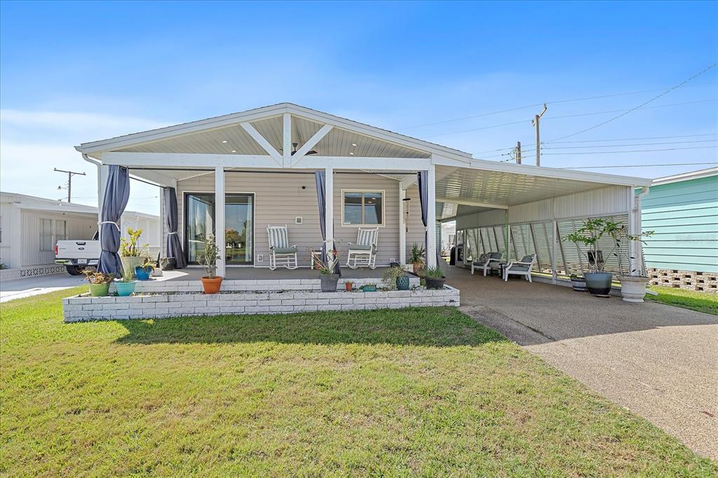 A single-story manufactured home features a covered front porch, a carport, and a concrete driveway — 137 LAKEVIEW DRIVE UNIT 137, PALMETTO, FL