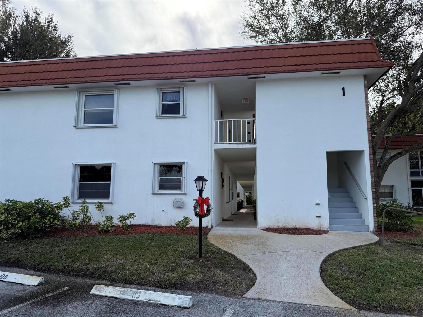 A two-story white apartment building with a red mansard roof and an exterior staircase — 1225 NW 21st Street # 103, Stuart FL 34994, STUART, FL
