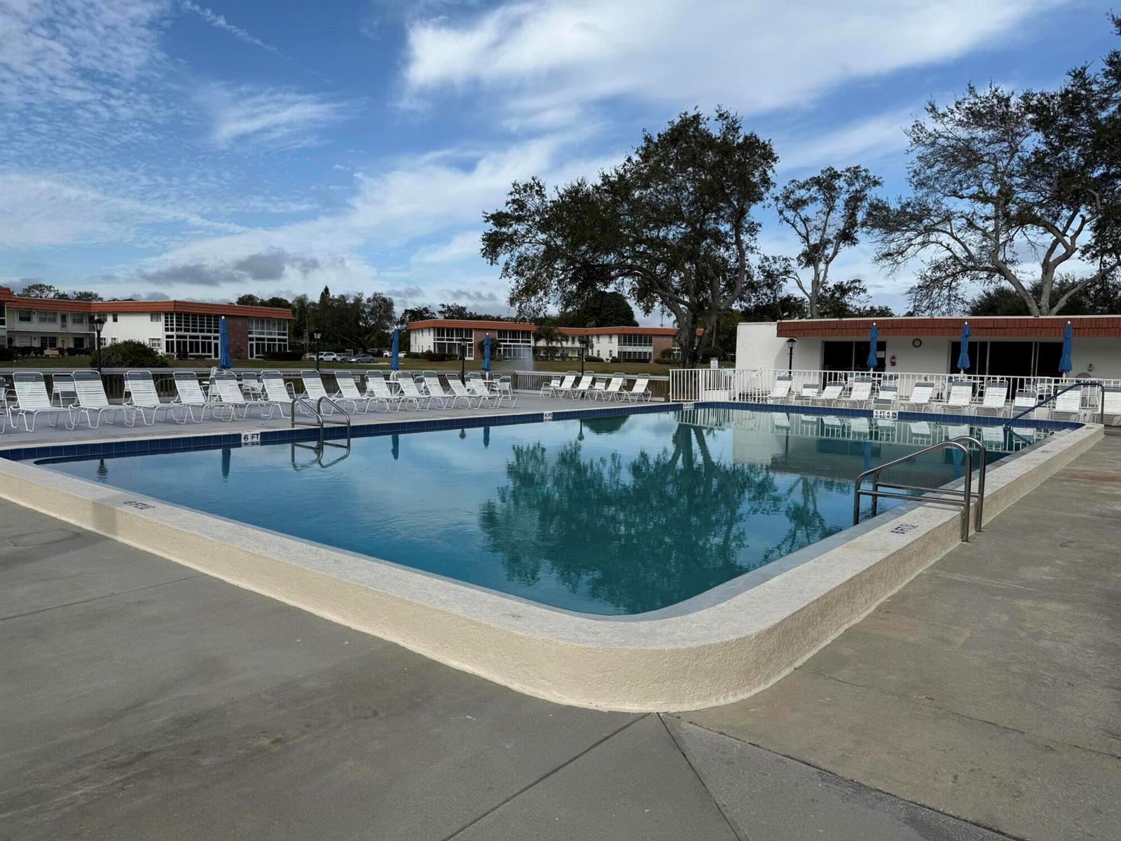 A rectangular outdoor swimming pool is surrounded by a concrete deck and lounge chairs — 1225 NW 21st Street # 103, Stuart FL 34994, STUART, FL
