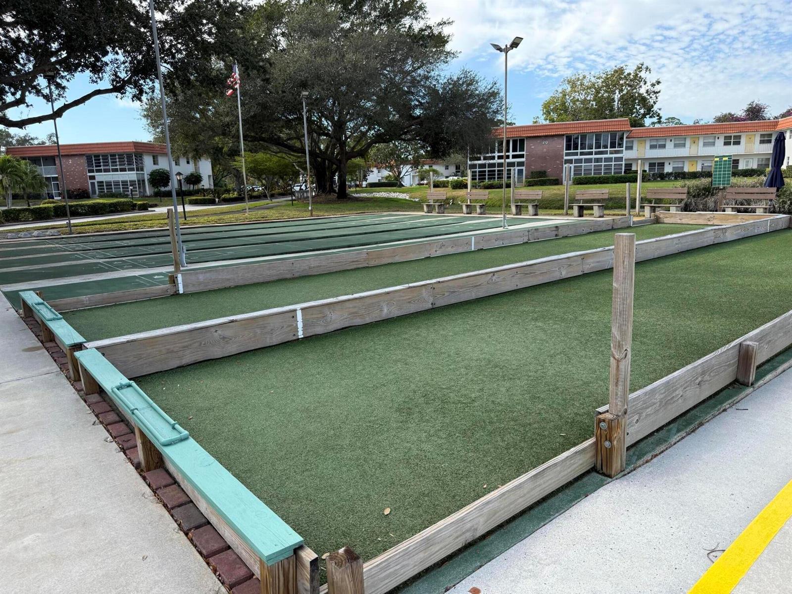 An outdoor bocce ball court with wooden borders and green turf sits before apartment buildings — 1225 NW 21st Street # 103, Stuart FL 34994, STUART, FL
