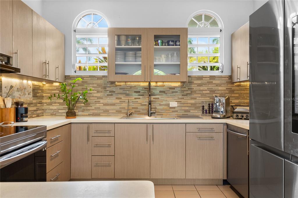 A kitchen features light wood cabinets, a mosaic tile backsplash, and two arched windows — 5 HARBOUR LIGHTS, HUMACAO, PR