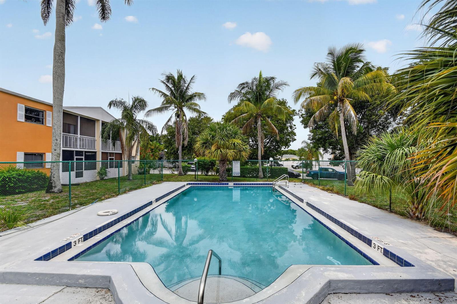 An outdoor rectangular swimming pool surrounded by a concrete deck and palm trees — 1505 Crescent Circle # B24, Lake Park FL 33403, LAKE PARK, FL