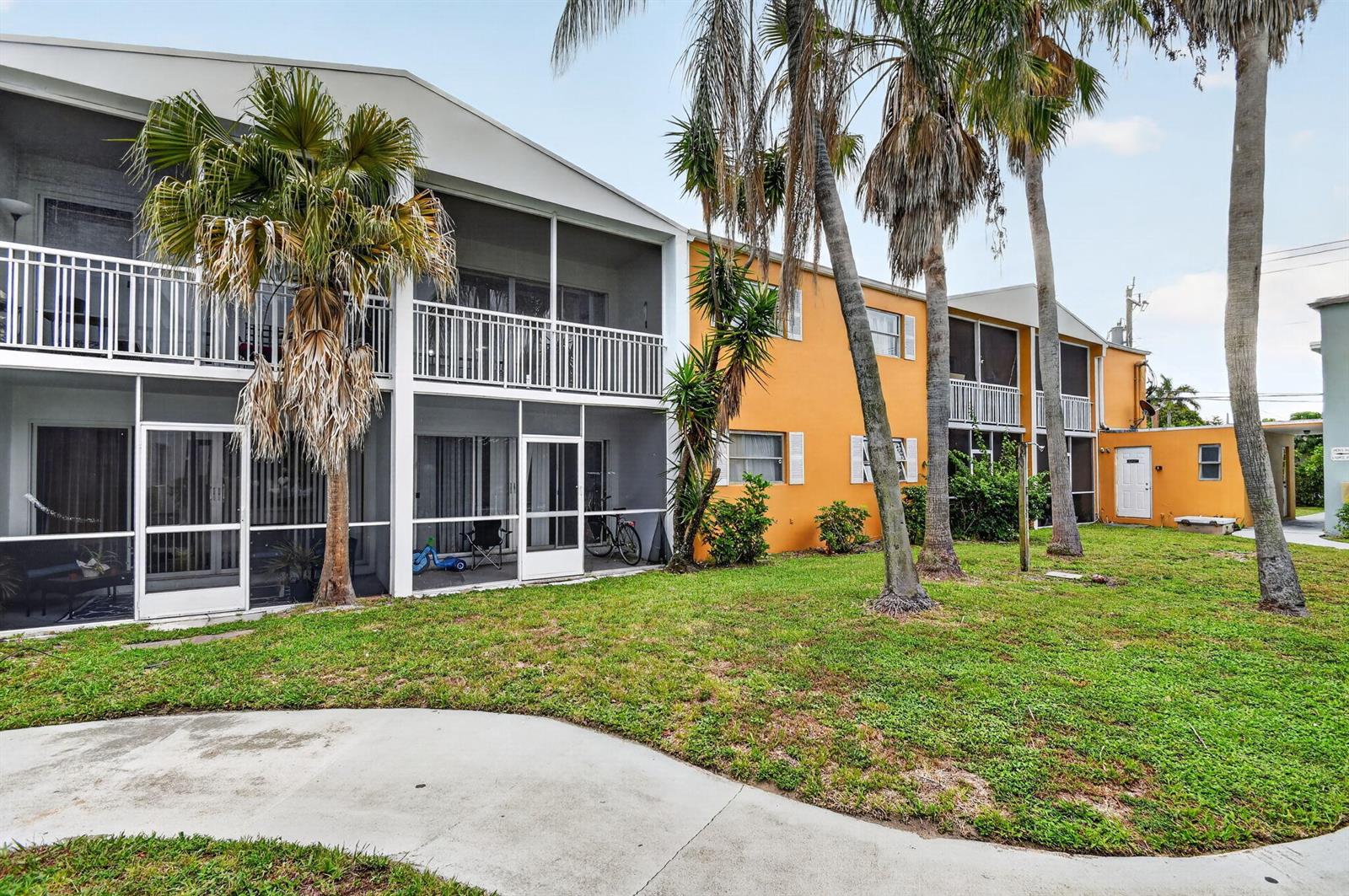 A two-story apartment building with screened balconies and orange exterior walls sits by a lawn — 1505 Crescent Circle # B24, Lake Park FL 33403, LAKE PARK, FL