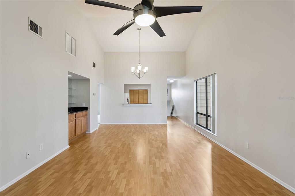 An empty living room with light wood flooring, a ceiling fan, and a wet bar — 2901 CLUBVIEW DRIVE UNIT U1, ORLANDO, FL