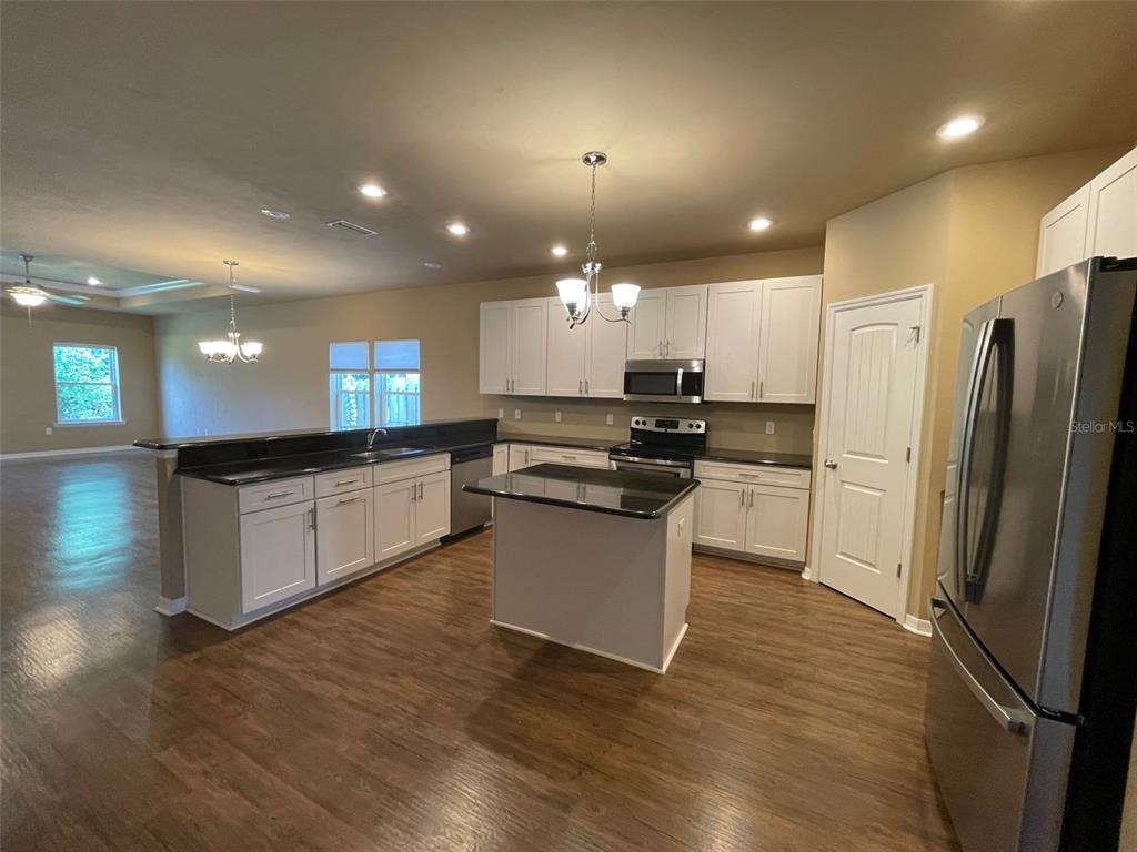 A kitchen with white cabinets, black countertops, a center island, and stainless steel appliances — 7879 SW 80TH DRIVE, GAINESVILLE, FL
