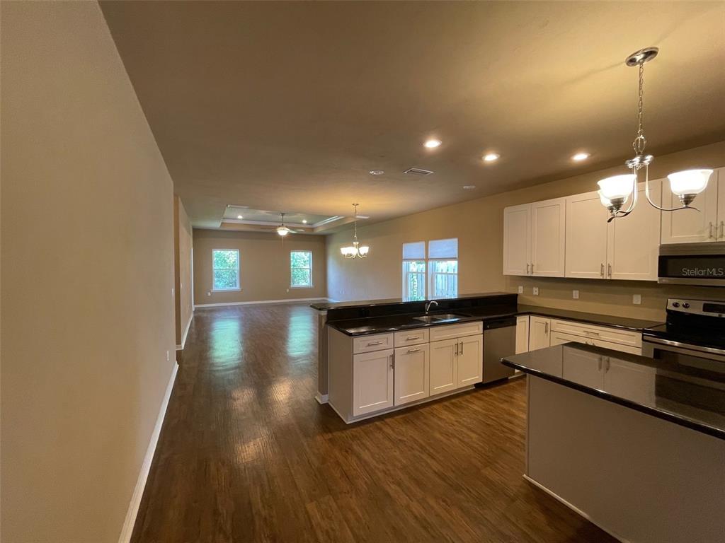 A kitchen with white cabinets and dark countertops opens into a spacious living area — 7879 SW 80TH DRIVE, GAINESVILLE, FL