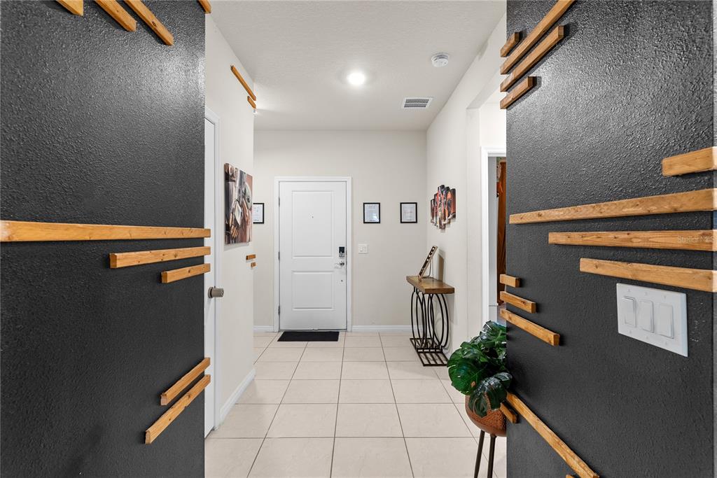 A foyer features light tile flooring, white walls, and dark accent walls with horizontal wood slats — 7614 OAK SPRING LANE, DAVENPORT, FL