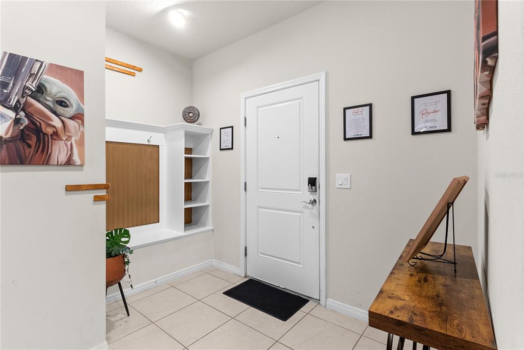 An entryway features a white door, a built-in bench with shelving, and a wooden console table — 7614 OAK SPRING LANE, DAVENPORT, FL