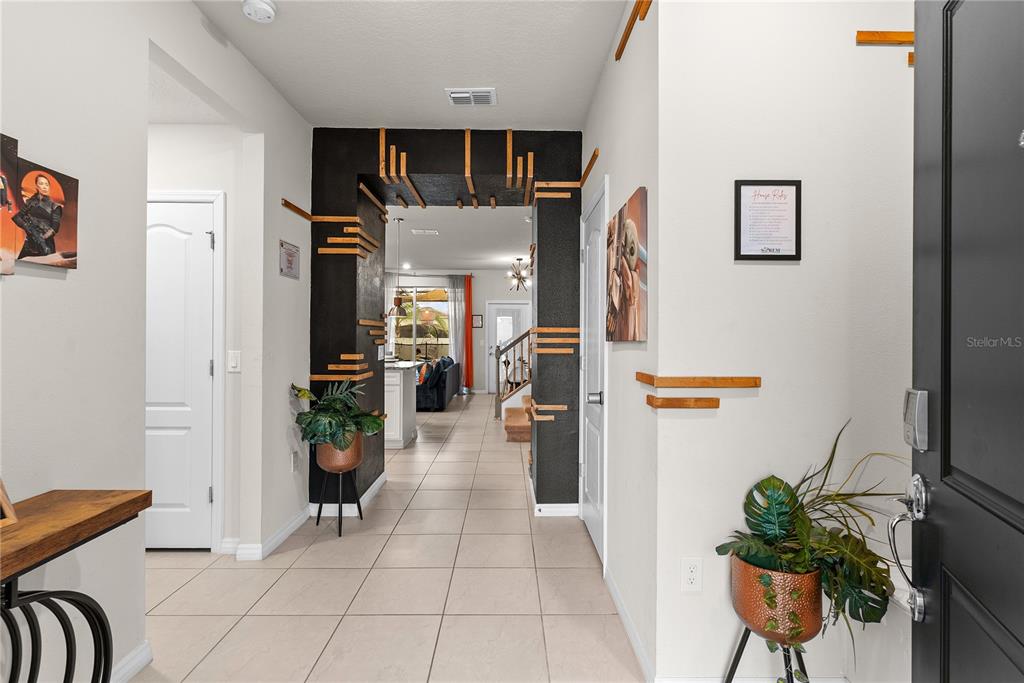 A tiled entryway features a black arched accent wall decorated with horizontal wooden slats — 7614 OAK SPRING LANE, DAVENPORT, FL