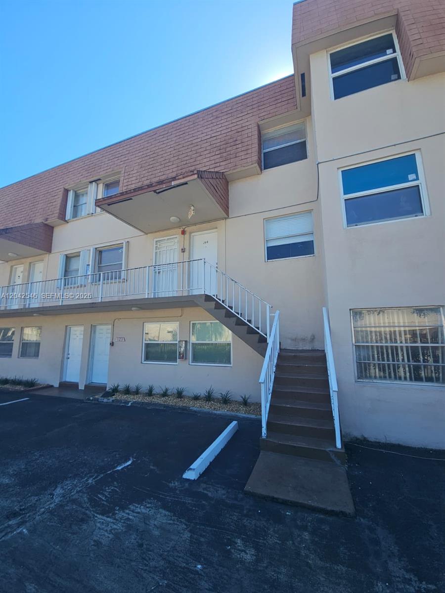 An exterior view of a multi-story apartment building with a concrete staircase and metal railings — 1560 W 46th St # 244, Hialeah FL 33012, HIALEAH, FL