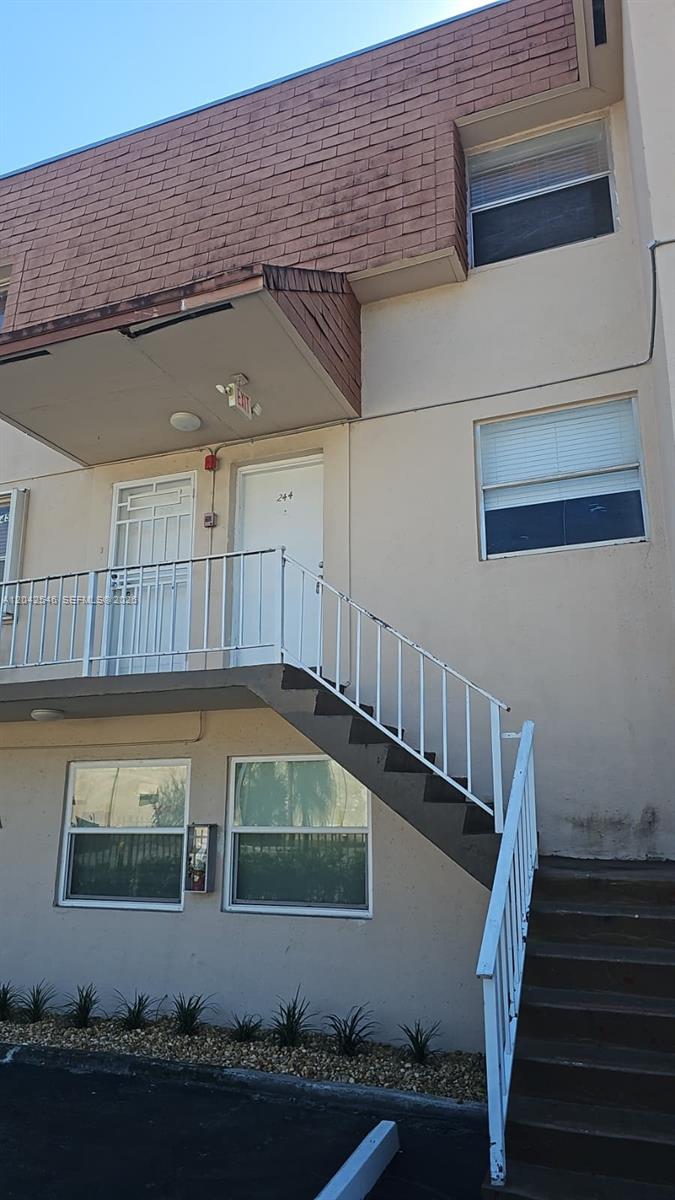 An exterior view of a two-story apartment building with a white staircase and balcony — 1560 W 46th St # 244, Hialeah FL 33012, HIALEAH, FL