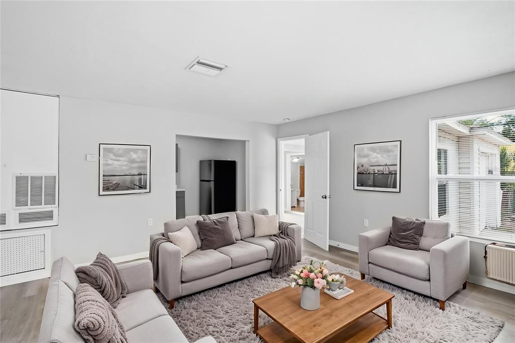 A living room features light gray walls, a gray sofa set, and a wooden coffee table — 3003 N ADAMS STREET, TAMPA, FL