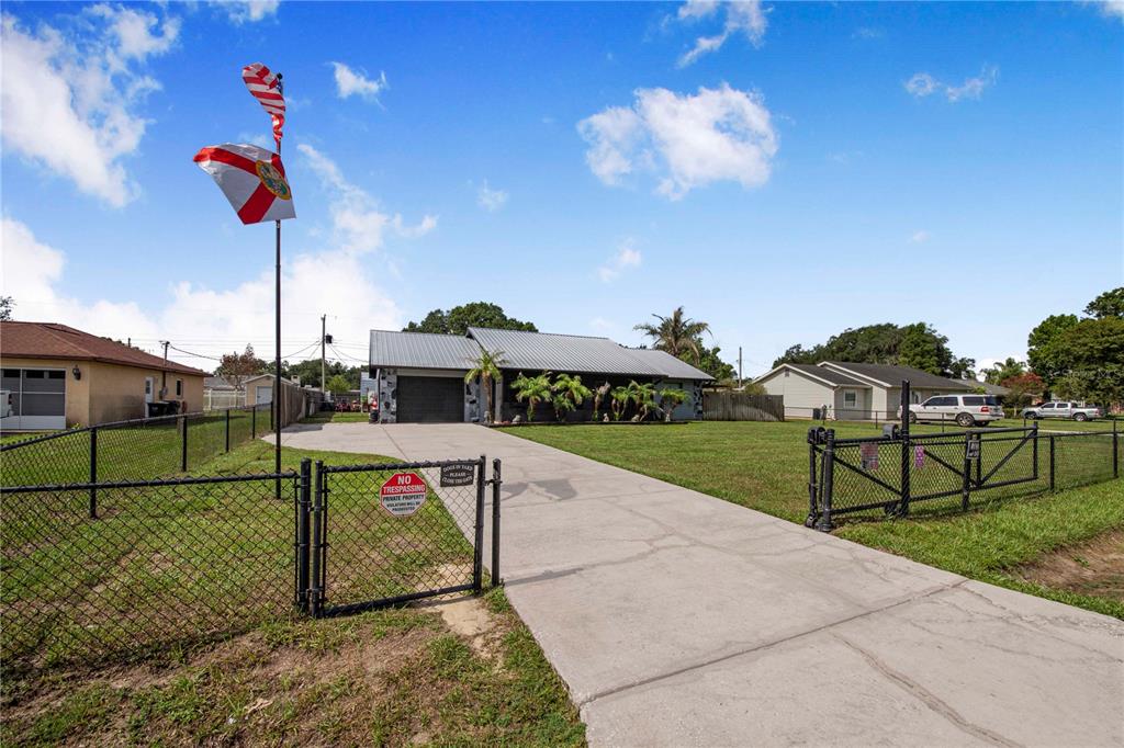 A single-story house with a metal roof and a fenced driveway in a grassy yard — 2426 VIEW WAY, LAKELAND, FL