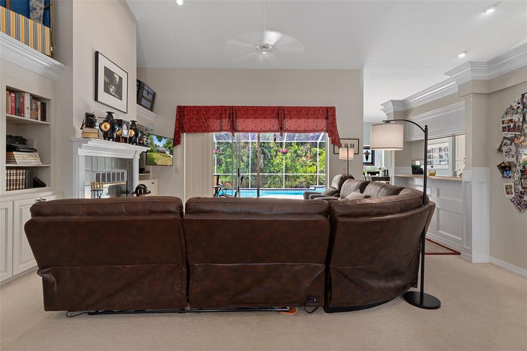 A living room features a brown leather sectional, a fireplace, and sliding doors to a pool — 2460 W PINE RIDGE BOULEVARD, BEVERLY HILLS, FL