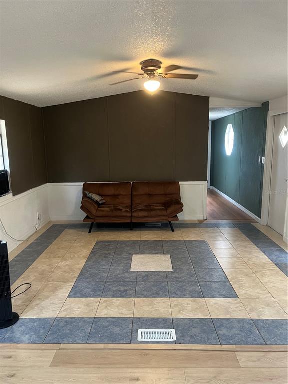 A living room features a brown sofa, a ceiling fan, and a tiled floor pattern — 10330 NE 90TH STREET, BRONSON, FL