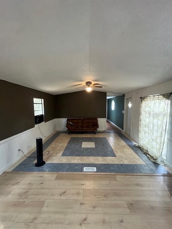A living room features a tiled center area, wood-look flooring, dark walls, and a ceiling fan — 10330 NE 90TH STREET, BRONSON, FL