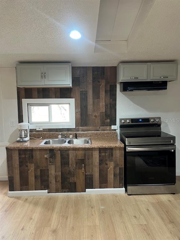 A kitchen features wood-plank cabinetry and backsplash, light-colored upper cabinets, and stainless steel appliances — 10330 NE 90TH STREET, BRONSON, FL