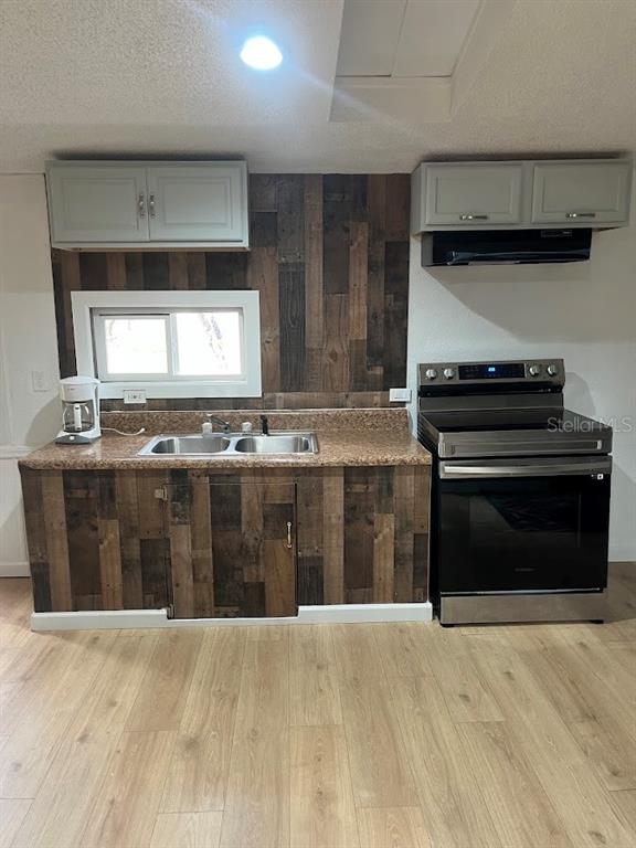 A kitchen features wood-paneled cabinetry and backsplash, a stainless steel stove, and light-colored flooring — 10330 NE 90TH STREET, BRONSON, FL