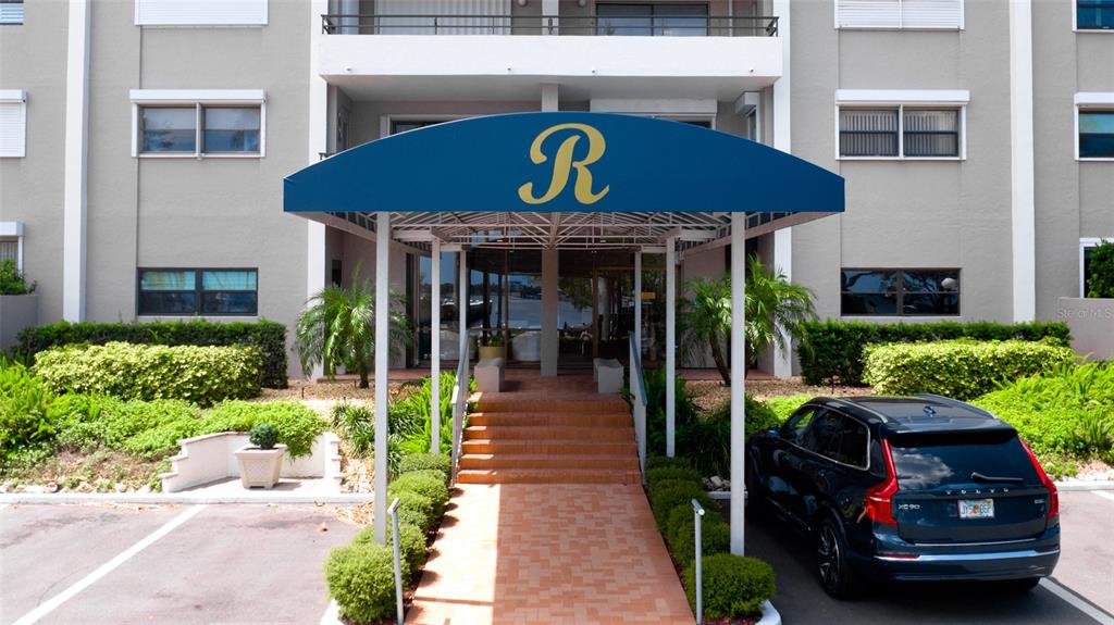 The exterior of a multi-story building features a blue awning with a large letter R — 1400 1ST AVENUE W UNIT 206, BRADENTON, FL