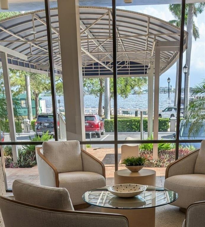 A seating area with armchairs and a glass coffee table overlooks a waterfront parking lot — 1400 1ST AVENUE W UNIT 206, BRADENTON, FL