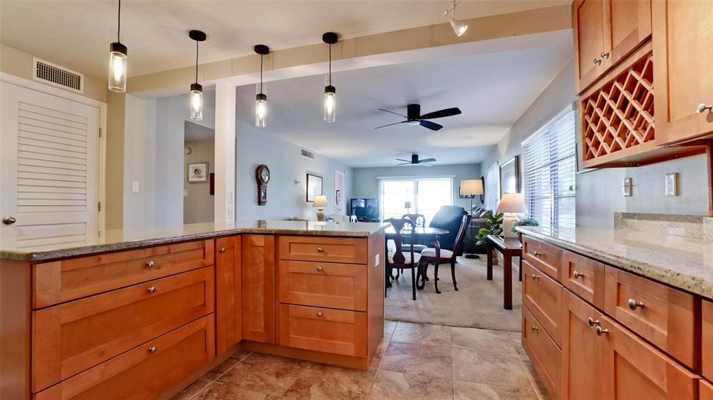 A kitchen with wood cabinets and granite countertops overlooks a dining area and living room — 1400 1ST AVENUE W UNIT 206, BRADENTON, FL