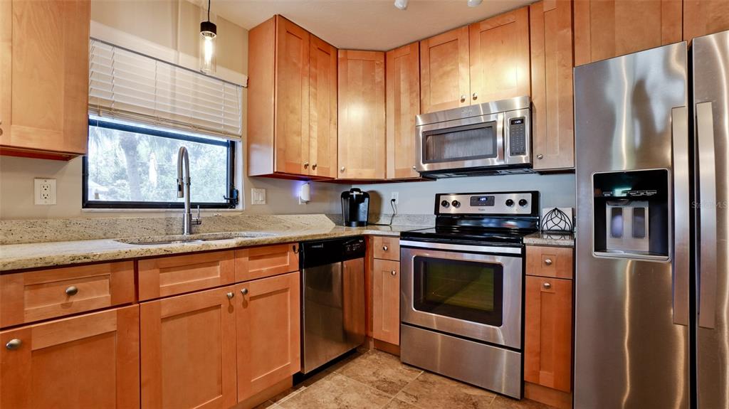 A kitchen features light wood cabinets, stainless steel appliances, and granite countertops — 1400 1ST AVENUE W UNIT 206, BRADENTON, FL