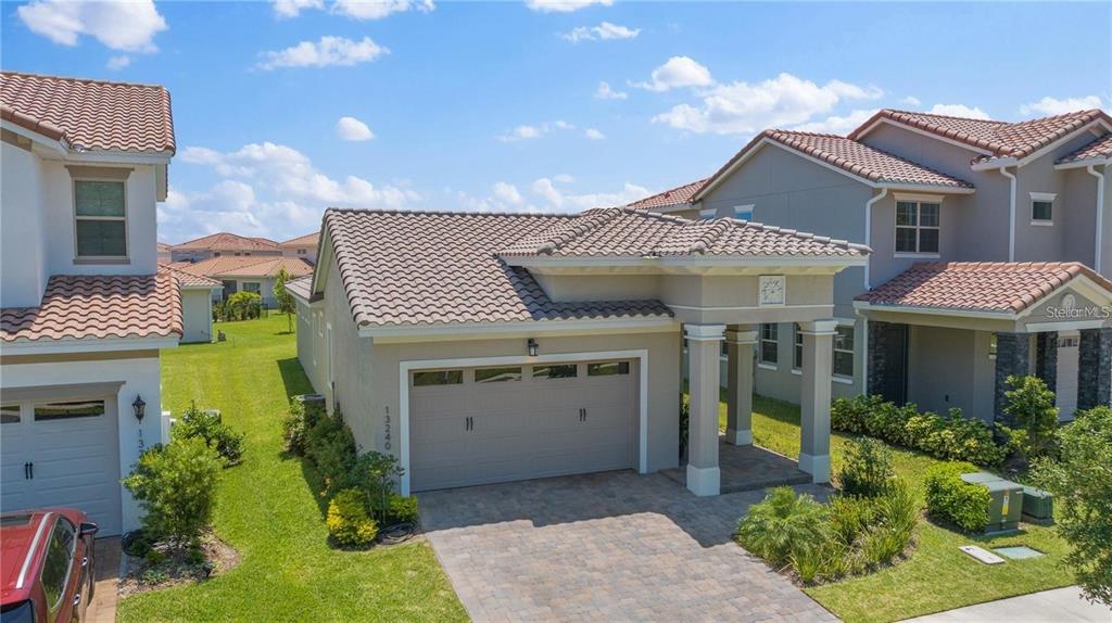 A single-story house with a tan stucco exterior, tile roof, and a two-car garage — 13240 BROMBOROUGH DRIVE, ORLANDO, FL