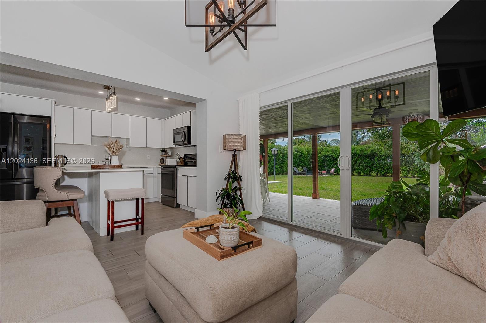 A living room with light tile floors opens to a kitchen and a backyard patio — 1130 NE 143rd St, North Miami FL 33161, NORTH MIAMI, FL