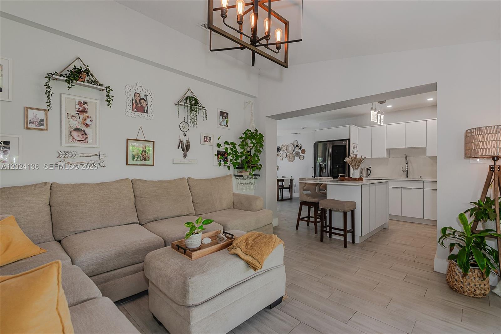 A living room with a beige sectional sofa opens into a modern white kitchen — 1130 NE 143rd St, North Miami FL 33161, NORTH MIAMI, FL