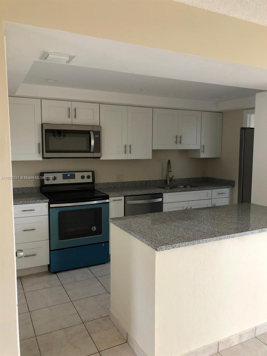 A kitchen features white cabinets, granite countertops, and stainless steel appliances — 8401 SW 107th Ave # 313E, Miami FL 33173, MIAMI, FL